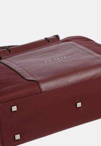 Borsa in pelle color bordeaux con design piatto, caratterizzata da dettagli in metallo quadrati argentati e cuciture in contrasto sul pannello frontale.