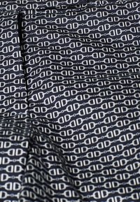 Tissu bleu marine avec un motif répétitif de chaînes blanches, composé de maillons circulaires et en forme de cœur, texture lisse, design uniforme sur toute la surface.