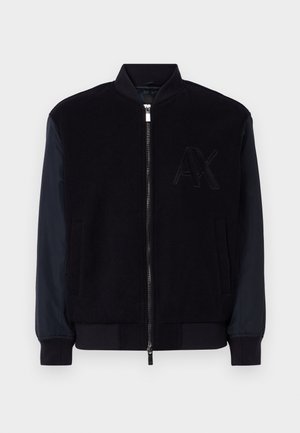 Giacca bomber nera con corpo in misto lana e maniche in nylon blu navy a contrasto. Presenta una cerniera frontale e un dettaglio discreto con il logo AX.