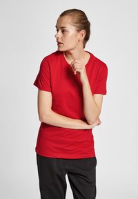 Rød bomulds T-shirt med korte ærmer, rund hals og en glat tekstur. Enkel design, bæres med sorte bukser. Passer til afslappet brug.