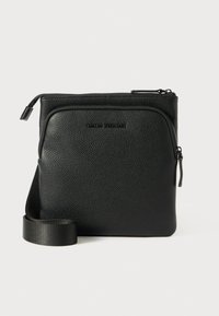 Čierna kožená crossbody taška s textúrovaným povrchom, predným zipsovým vreckom a nastaviteľným, plochým ramenným popruhom.