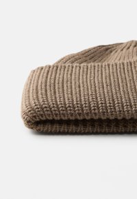 Gorro de malha castanho com textura canelada e lã espessa e macia. A aba dobrada confere estrutura ao design.