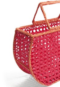Czerwony pleciony kosz z zaokrągloną podstawą, z jaśniejszą różowobrązową lamówką i dwoma krótkimi uchwytami. Całość o otwartej konstrukcji kratowej.