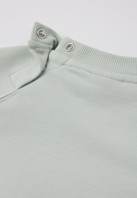 Lichtgroene sweatshirtstof met een gladde textuur, voorzien van drukknoopsluiting bij de kraag en een geribde halslijn.