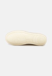 Suola di una sneaker in gomma avorio. Presenta un battistrada decorato con motivi circolari e lineari. Include il nome del marchio "AUTRY" in rilievo.