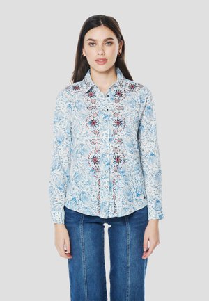 Camisa de manga larga con botones en azul claro con patrones ondulados y bordado floral rojo en la parte delantera. Tela de algodón, corte holgado.