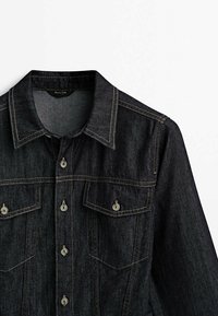 Czarna dżinsowa kurtka z guzikami przy kołnierzu oraz kieszeniami na piersi, z kontrastowymi przeszyciami i jasnymi guzikami.