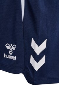 Tumši zils sporta audums ar reljefu adījumu, ar baltu "hummel" bišu logotipu un divām baltām leju vērstām šķautnēm sānos.