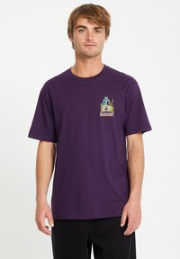 Lila Baumwoll-T-Shirt mit kurzen Ärmeln und Rundhalsausschnitt, das einen bunten Grafikdruck im Bereich der linken Brust aufweist.