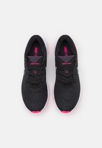 Mustat urheilukengät, joissa on verkkopäällinen ja vaaleanpunaiset yksityiskohdat. Ne sisältävät tekstuurillisen muotoilun, pehmustetun pohjan ja sivussa olevan logon.