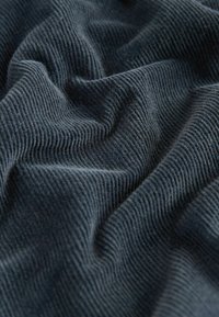 Tessuto a coste di un grigio scuro con una consistenza morbida, caratterizzato da linee verticali prominenti e un aspetto leggermente stropicciato.