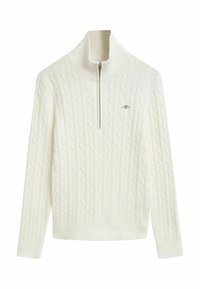Cremefarbenes Kabelstrickpullover mit hohem Kragen, der einen halben Reißverschluss vorne hat, sowie gerippten Bündchen und Saum. Dezentes Logo auf der Brust.