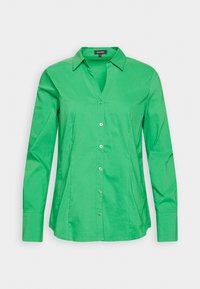 Chemise verte à manches longues, boutonnée, avec col, taille cintrée et poignets boutonnés, présentée sur fond blanc.
