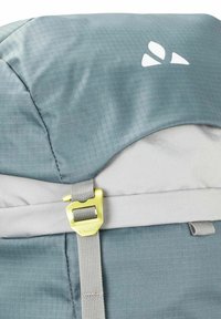 Grauer Rucksack mit diamantförmigem Muster, einer großen runden Oberseite und einer gelben Hardware-Schnalle, mit einem in Weiß gedruckten Logo.