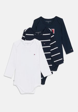 Drei Babybodys mit langen Ärmeln, einer in Weiß, einer in Marineblau mit weißen Streifen und einer in einfarbigem Marineblau mit einem rot-weißen Logo.