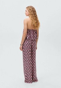 Jumpsuit bez naramenica s raširenim donjim dijelom u tamnom materijalu, s rozo-paisley uzorkom po cijeloj površini i nabranim gornjim dijelom.