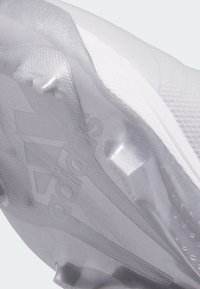 Zapatilla deportiva blanca con una suela translúcida y texturizada que muestra la marca "adidas". Presenta un diseño elegante y elementos de tracción detallados.