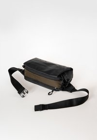 Borsa a tracolla nera e verde oliva con chiusura a rotolo, tracolla regolabile e scomparti con zip. Realizzata in materiale durevole.