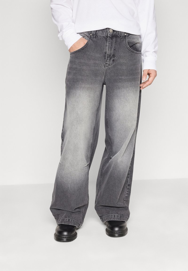 Sackiga grå jeans i denim med en blekt gradienteffekt, fem fickor och knäppning med knapp. Bärs med svarta skor.