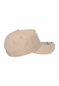 Cappellino da baseball beige con visiera curva, realizzato in cotone, con superficie texturizzata e una piccola toppa con logo nella parte frontale.