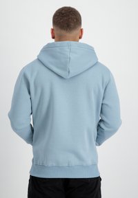 Sudadera con capucha de color azul claro, con una textura suave, bolsillo tipo canguro, mangas y dobladillo acanalados, vista desde la parte de atrás.