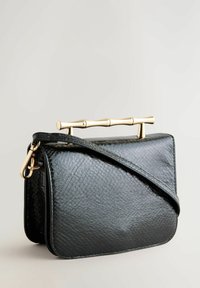 Černá kabelka z umělé kůže s texturovaným povrchem, vybavená zlatým bambusovým madlem a odnímatelným ramenním popruhem.