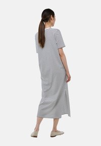 Robe maxi rayée en tissu noir et blanc, offrant une coupe décontractée, des manches courtes et une fente latérale pour plus de facilité de mouvement.