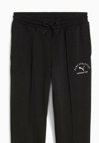 Svarta sweatpants tillverkade av mjukt, texturerat tyg. Har ett elastiskt midjeband med dragsnöre, sidofickor och en vit logotyp på låret.