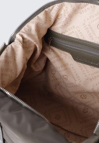 Grijze handtas met een gladde buitenkant, open rits en een beige binnenvoering met een herhalend logopatroon. Inclusief een binnenzak met rits.