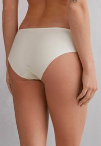Högmidjade shorts i mjukt, ljusbeige tyg. Slät textur, minimal sömnad och rundad bakdel för en sömlös passform.