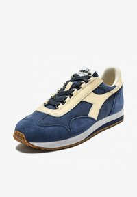 Sneaker con tomaia in suede blu navy e dettagli in pelle crema. Presenta lacci testurizzati e una suola in gomma marrone, con logo sulla linguetta.