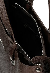 Borsa in pelle marrone con esterno testurizzato, hardware argentato e una tasca con zip interna. Design aperto con due manici.