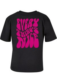 Černé bavlněné tričko s velkým, výrazným růžovým grafickým textovým designem na zadní straně, který zní "VŠECHNO JE HEZKÉ". Krátké rukávy.