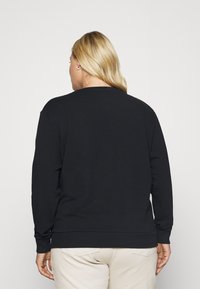Felpa nera con maniche lunghe, polsini e orlo a coste, dotata di scollatura a girocollo e texture liscia. Il design sul retro è minimalista.