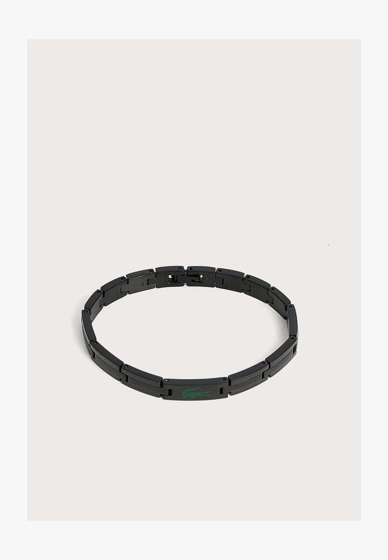 Bracelet à maillons en métal noir avec un logo crocodile vert sur un maillon rectangulaire sur fond blanc.
