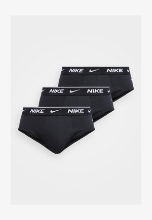 Tre slip neri Nike con logo bianco Nike e swoosh sulla fascia in vita, disposti sovrapposti su uno sfondo chiaro.