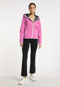 Fuchsia zip-up jasje met capuchon, witte accenten, twee voorzakken; gecombineerd met zwarte flared broeken en witte sneakers.