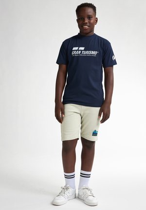 Granatowy bawełnowy t-shirt z białym napisem "Gran Turismo", w połączeniu z jasnoskalnymi szortami z wielobarwnym logo palmy i paskowanymi skarpetkami.