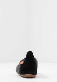 Grijze wollen slipper met een zwarte suede hak en een bruine leren accent. Lichtjes toegespitste achterkant, platte rubberen zool en een naadloos ontwerp.