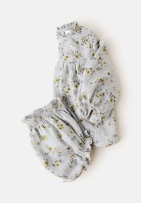 Harmaa kukkakuosisetti, jossa on röyhelökauluksellinen paita ja siihen sopivat joustovyötäröiset shortsit, valmistettu kevyestä kankaasta.