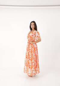 Robes maxi fleuries en orange et bleu clair, avec un décolleté en V et de courtes manches flottantes, cintrées à la taille pour une silhouette fluide.