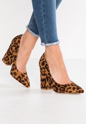 Scarpe con tacco alto in stampa leopardata, con punta arrotondata, texture in suede e tacco spesso. Schema di colori marrone e nero con finitura liscia.