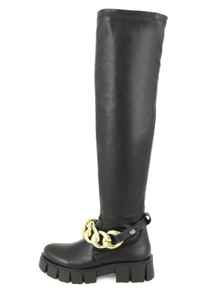 Stivale in pelle nera alti fino alla coscia con suola nera spessa, caratterizzato da un grande accento di catena dorata attorno alla caviglia. Texture liscia e design minimale.