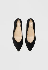 Μαύρα μοκασίνια από καστόρι με μυτερό δάχτυλο και άνοιγμα σε σχήμα V. Διαθέτουν μπεζ εσωτερική σόλα και χρυσό λογότυπο της μάρκας, με λείο υφή σε όλο το υπόδημα.