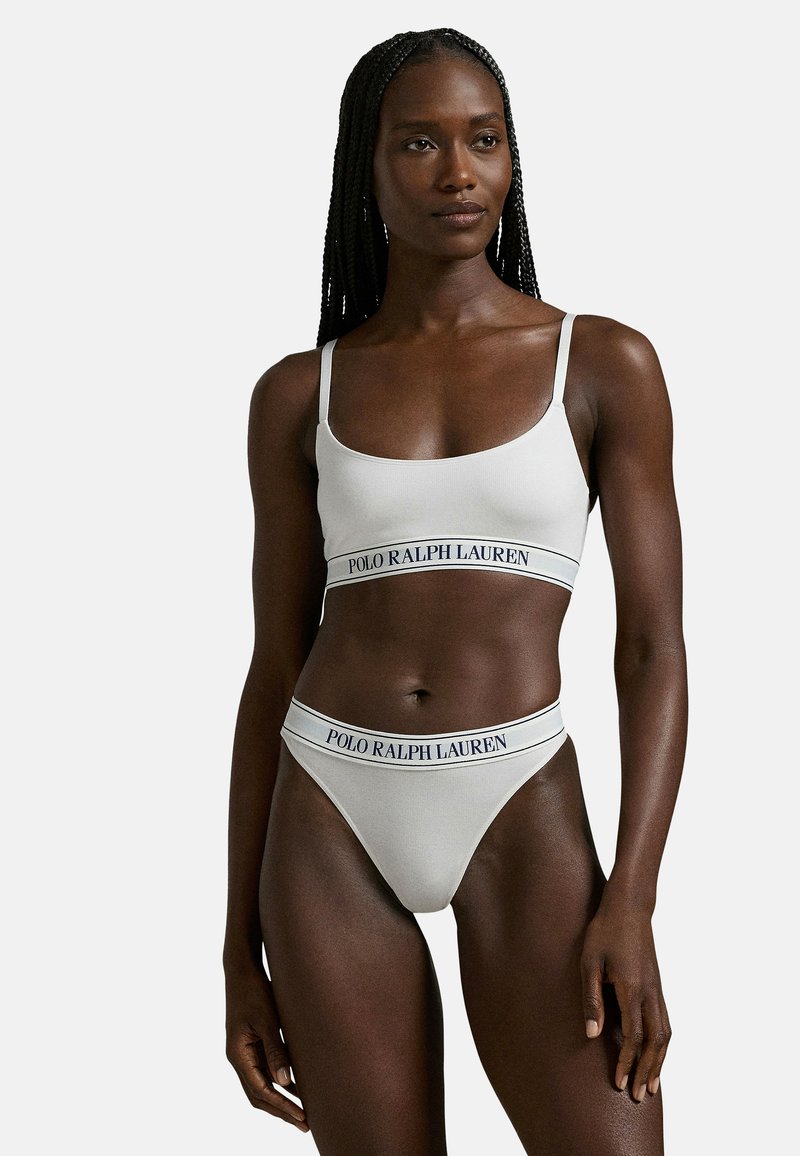 Vaaleanharmaa rintaliivien ja stringien setti, jossa säädettävät olkaimet ja joustava nauha, jossa on "POLO RALPH LAUREN" -brändäys laivastonsinisellä. Sileä tekstuuri.