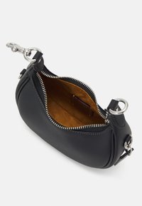 Musta nahkainen laukku, jossa on hopeiset yksityiskohdat, vetoketjukiinnitys ja pehmeä ruskea vuori. Ominaisuuksiin kuuluu pyöreä muoto ja sivukiinnityssilmukka.