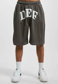 Grå shorts laget av myk stoff, med hvit "DEF" skrift på baksiden, og med elastisk midjebånd og løs passform.