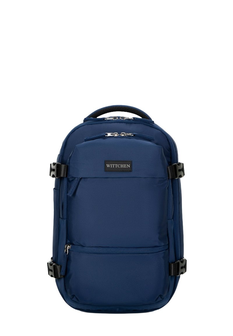Námořnická modrá nylonová batoh s několika zipovými přihrádky, nastavitelnými popruhy, texturovanou rukojetí a černou logo nášivkou na přední straně.