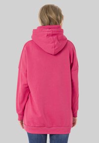 Übergroßer pinker Hoodie mit einer Kordelzugkapuze und gerippten Bündchen, gestaltet mit einem lässigen Schnitt und aus glattem Baumwollmischmaterial.