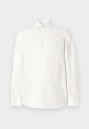 Hvit skjorte med lange ermer laget av glatt stoff. Har spiss krage, knappelukking foran og avrundet kant. Ingen synlige mønstre.